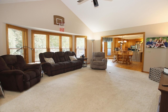 carpeted living room with high vaulted ceiling and ceiling fan with notable chandelier