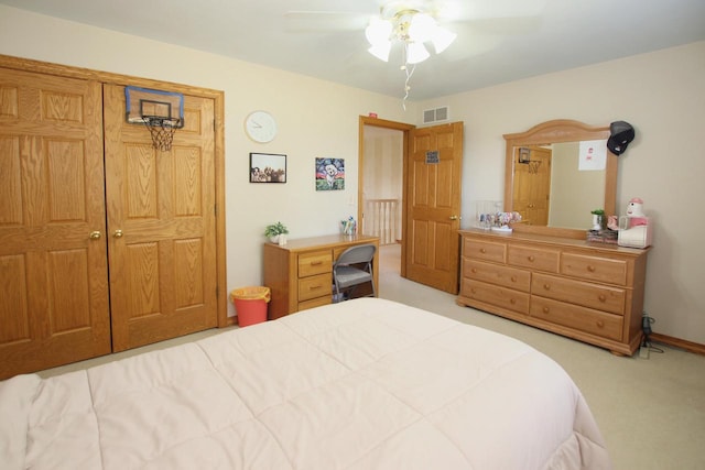 bedroom with ceiling fan, light colored carpet, and a closet