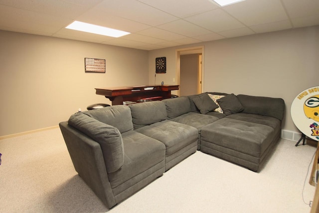 living room featuring a drop ceiling and carpet