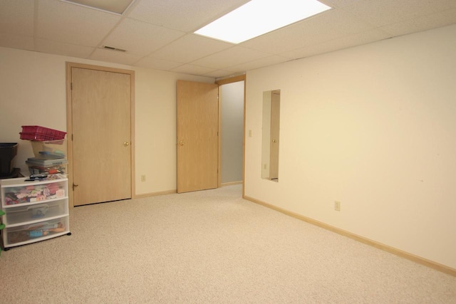 basement featuring carpet, a paneled ceiling, and electric panel