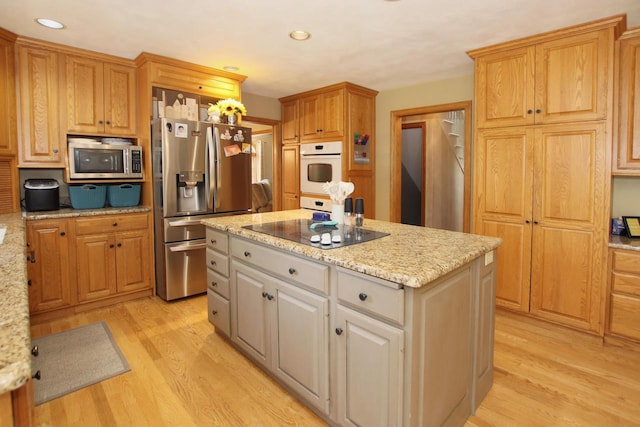 kitchen featuring a center island, light stone countertops, light hardwood / wood-style floors, and appliances with stainless steel finishes