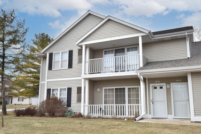 view of front of property featuring a balcony and a front yard