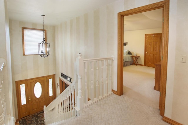 hall with light carpet and an inviting chandelier