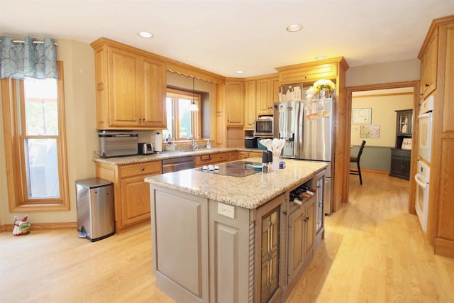 kitchen with a kitchen island, a healthy amount of sunlight, stainless steel appliances, and light hardwood / wood-style flooring