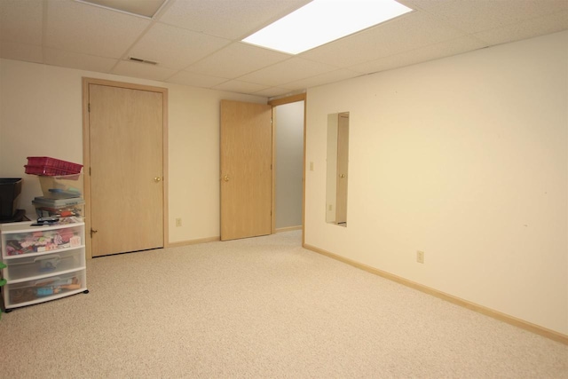 basement featuring carpet flooring, a paneled ceiling, and electric panel