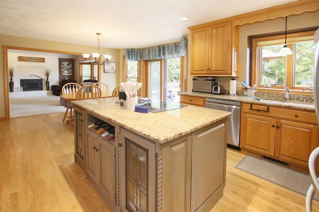 kitchen with sink, a kitchen island, stainless steel dishwasher, and decorative light fixtures