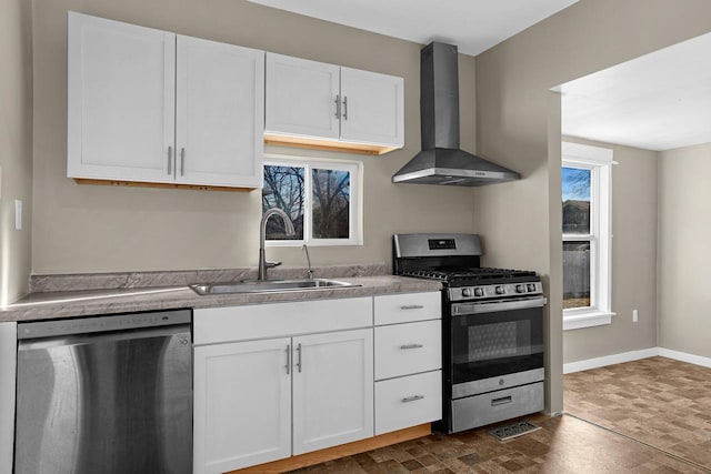 kitchen with white cabinetry, sink, stainless steel appliances, and wall chimney range hood