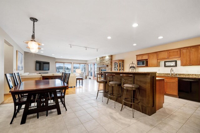 kitchen with light stone countertops, pendant lighting, dishwasher, sink, and rail lighting