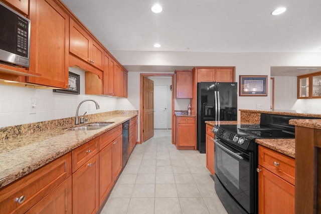 kitchen featuring black appliances, light stone countertops, and sink