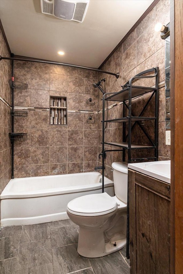 full bathroom with vanity, tiled shower / bath combo, tile walls, and toilet