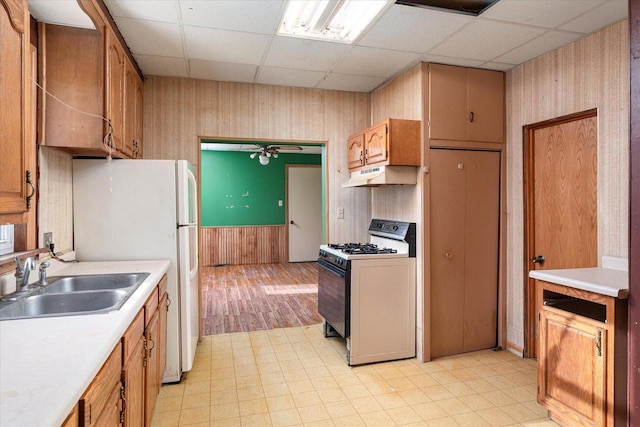 kitchen with ceiling fan, sink, wood walls, stove, and a paneled ceiling