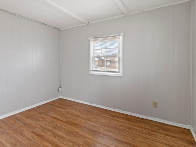 spare room featuring beamed ceiling and hardwood / wood-style flooring