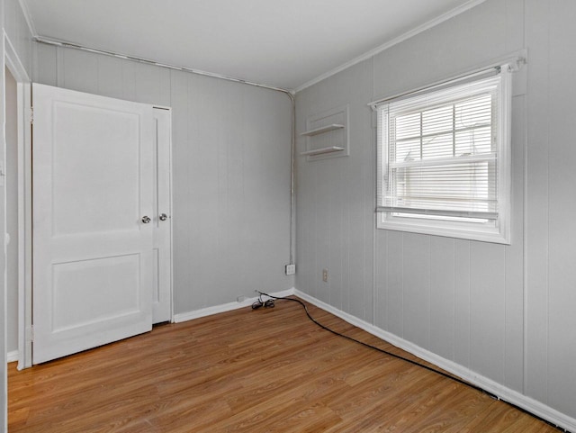 empty room featuring crown molding and light hardwood / wood-style flooring