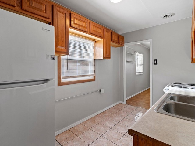 kitchen featuring white fridge, light tile patterned floors, and sink