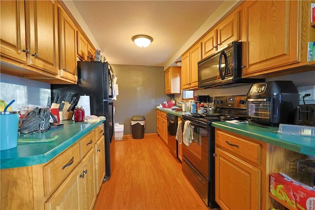 kitchen with light hardwood / wood-style floors and black appliances