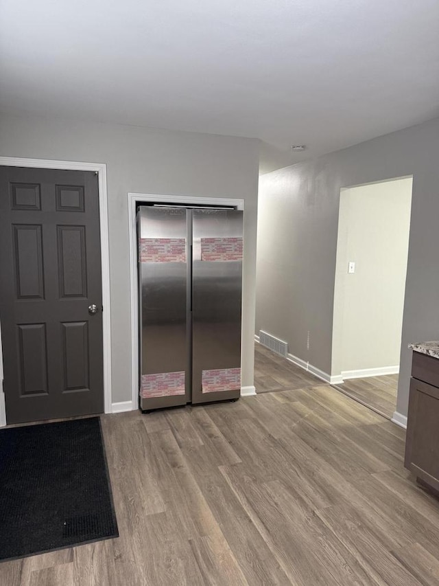 kitchen featuring stainless steel fridge and light hardwood / wood-style flooring