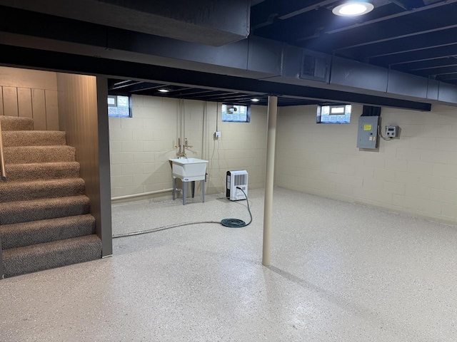 basement featuring electric panel, a wealth of natural light, and sink