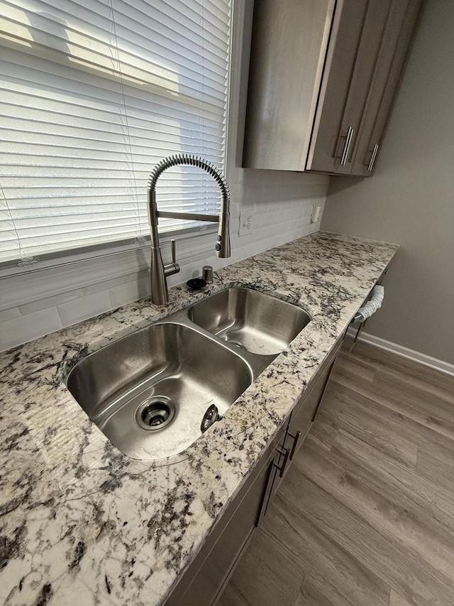 interior details featuring light stone countertops, dark brown cabinets, dark hardwood / wood-style floors, and sink