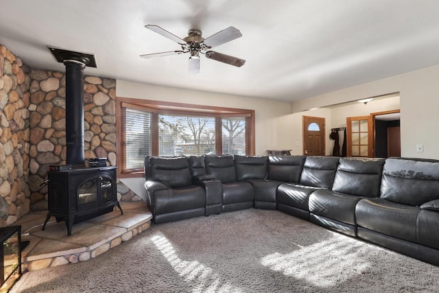 carpeted living room featuring a wood stove and ceiling fan