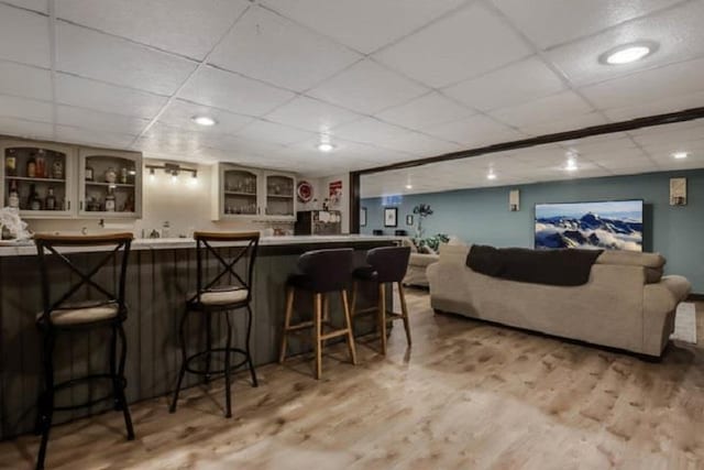 bar with light hardwood / wood-style floors and a drop ceiling