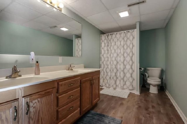 bathroom with walk in shower, a drop ceiling, vanity, hardwood / wood-style floors, and toilet