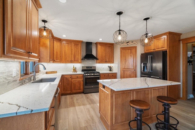 kitchen with a sink, stainless steel appliances, wall chimney range hood, light wood-type flooring, and a center island