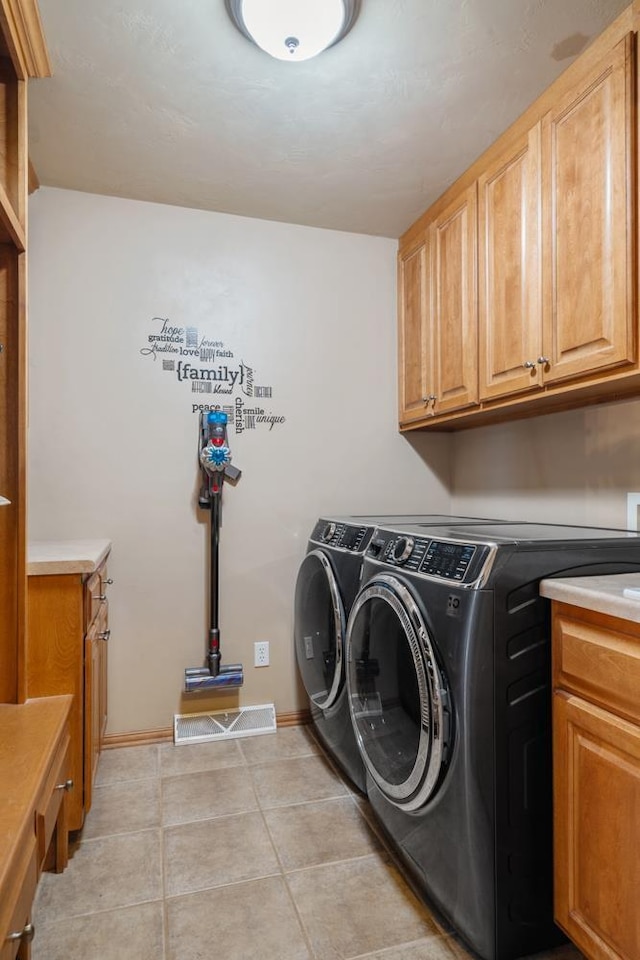 clothes washing area with visible vents, washer and dryer, cabinet space, light tile patterned flooring, and baseboards