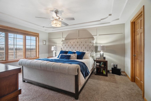 bedroom with a tray ceiling, ceiling fan, and carpet floors