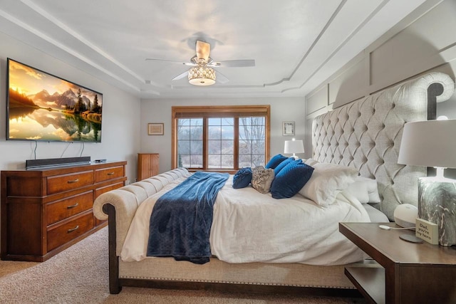 carpeted bedroom with a tray ceiling and ceiling fan