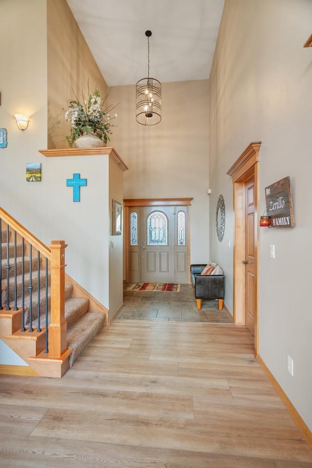 entrance foyer featuring a notable chandelier, a towering ceiling, and light hardwood / wood-style flooring