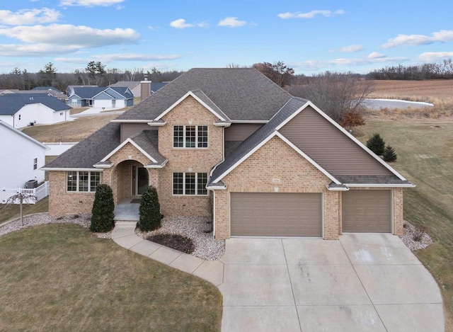 traditional home featuring a chimney, concrete driveway, a front yard, and a garage