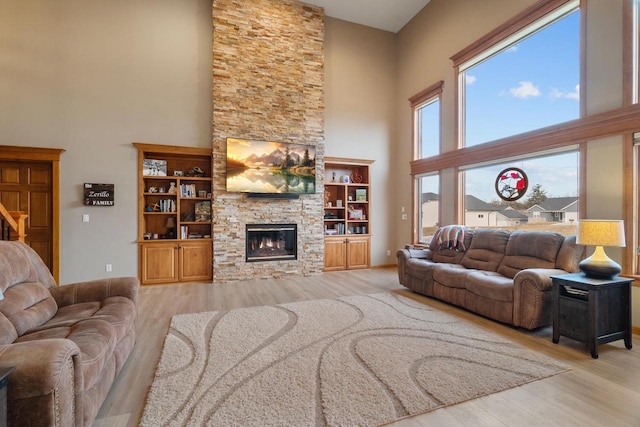 living room with a fireplace, wood finished floors, and a towering ceiling