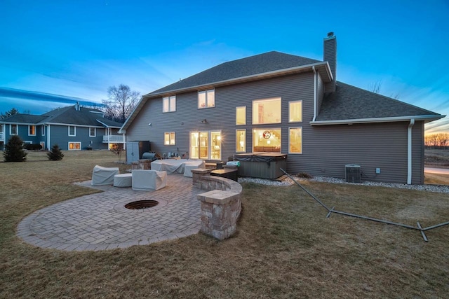 back of house with a hot tub, a shingled roof, a lawn, a chimney, and a patio area