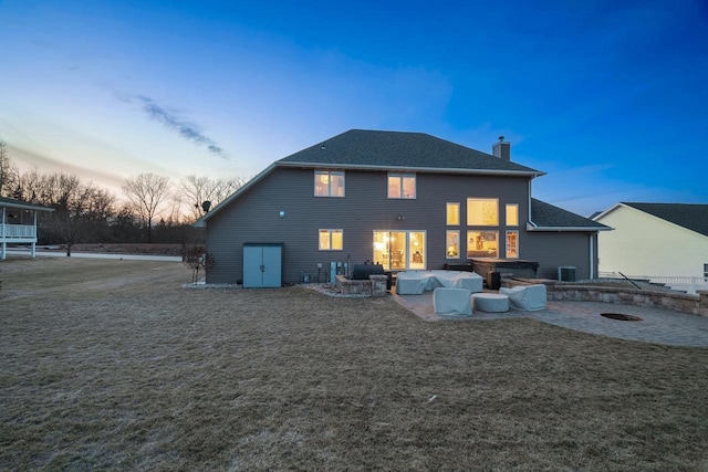 back house at dusk featuring outdoor lounge area and a patio area