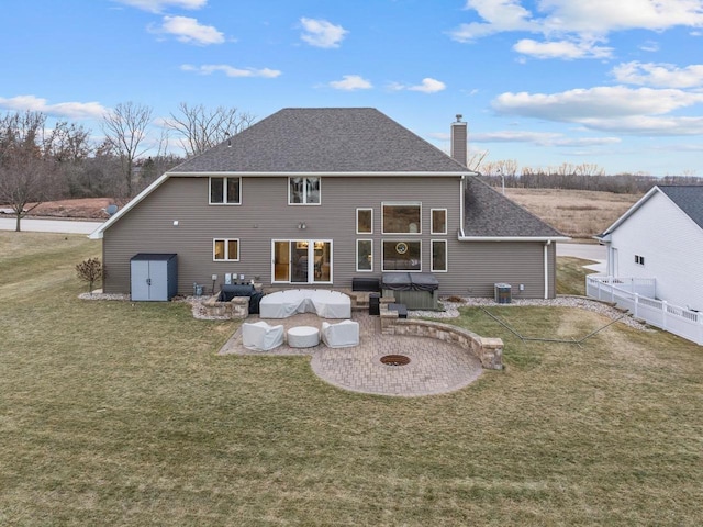 back of house featuring fence, roof with shingles, a chimney, a hot tub, and a lawn