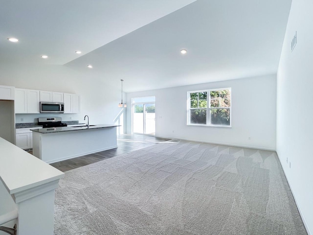 kitchen featuring an island with sink, stainless steel appliances, pendant lighting, white cabinets, and sink