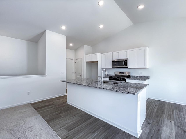 kitchen with appliances with stainless steel finishes, dark stone counters, sink, white cabinetry, and an island with sink