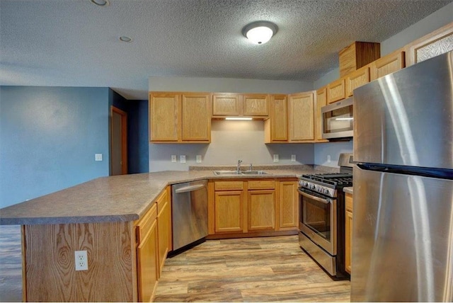 kitchen featuring sink, light brown cabinetry, appliances with stainless steel finishes, light hardwood / wood-style floors, and kitchen peninsula