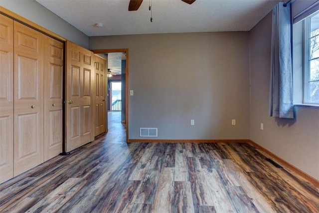 unfurnished bedroom with dark hardwood / wood-style flooring, ceiling fan, a closet, and a textured ceiling