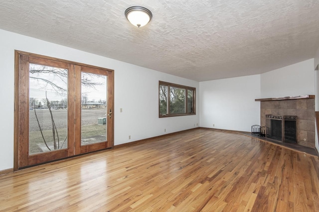 unfurnished living room with a textured ceiling, a fireplace, and light hardwood / wood-style flooring