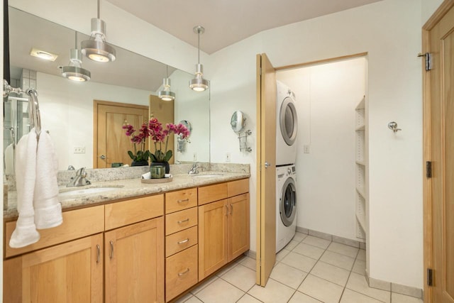 laundry area featuring light tile patterned floors, stacked washing maching and dryer, and sink