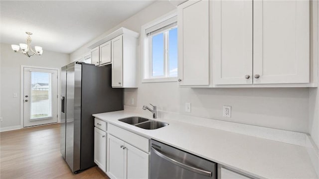 kitchen with an inviting chandelier, decorative light fixtures, dishwasher, white cabinets, and sink