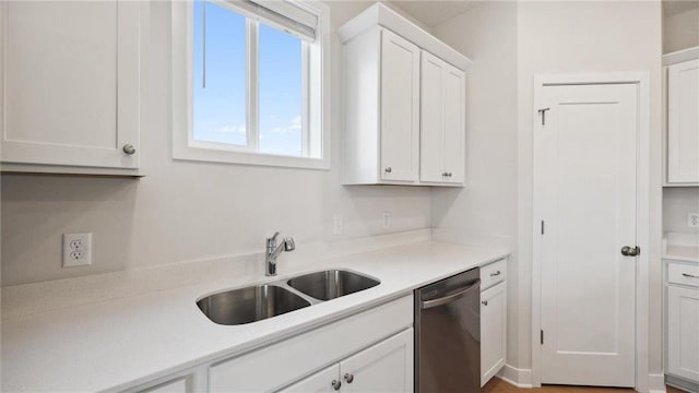 kitchen featuring stainless steel dishwasher, sink, and white cabinetry