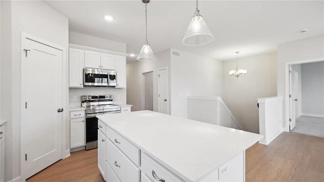 kitchen featuring pendant lighting, white cabinets, stainless steel appliances, and a kitchen island