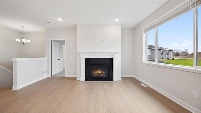 unfurnished living room featuring light hardwood / wood-style floors and a chandelier