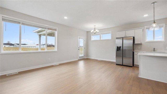 kitchen with hanging light fixtures, stainless steel fridge with ice dispenser, an inviting chandelier, and white cabinetry