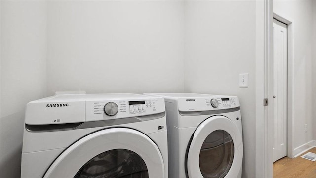 clothes washing area with independent washer and dryer and light wood-type flooring