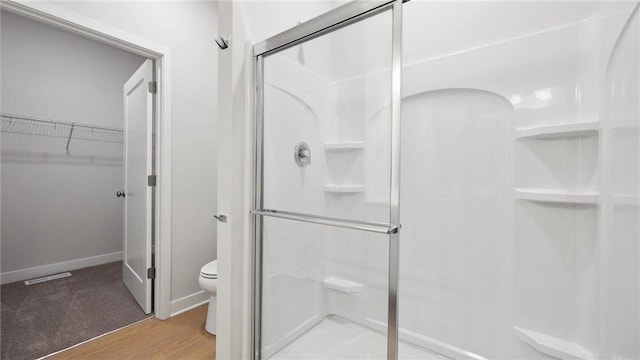 bathroom featuring hardwood / wood-style flooring, toilet, and a shower with door