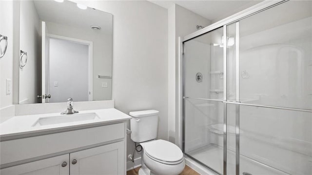 bathroom with toilet, vanity, and an enclosed shower