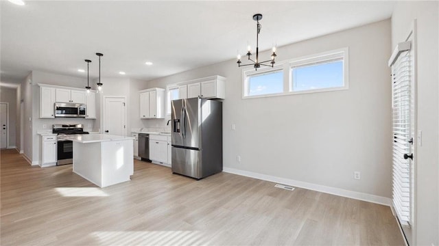 kitchen with a kitchen island, white cabinetry, stainless steel appliances, and hanging light fixtures